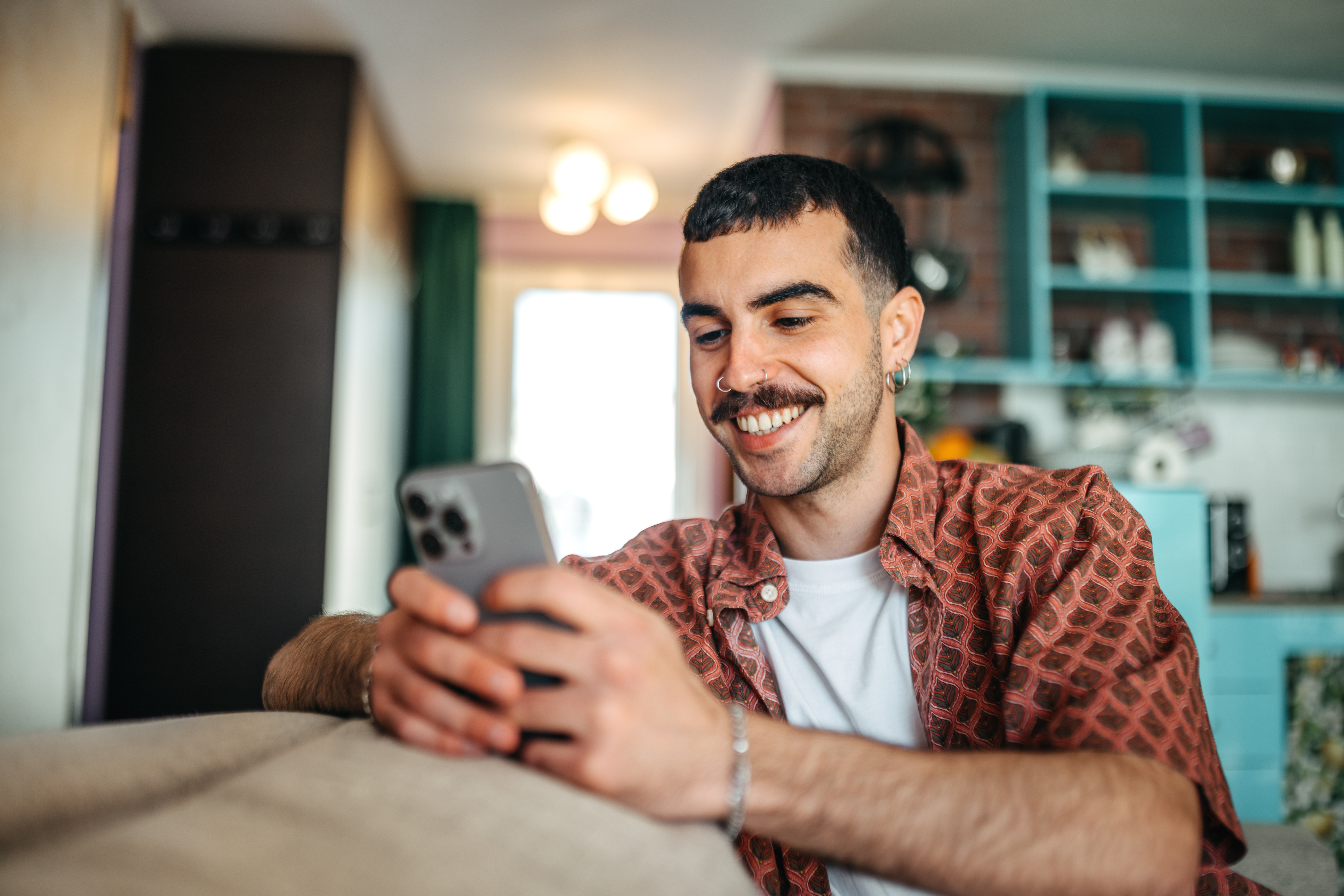 A man smiles at a phone while learning about FHA loan options.