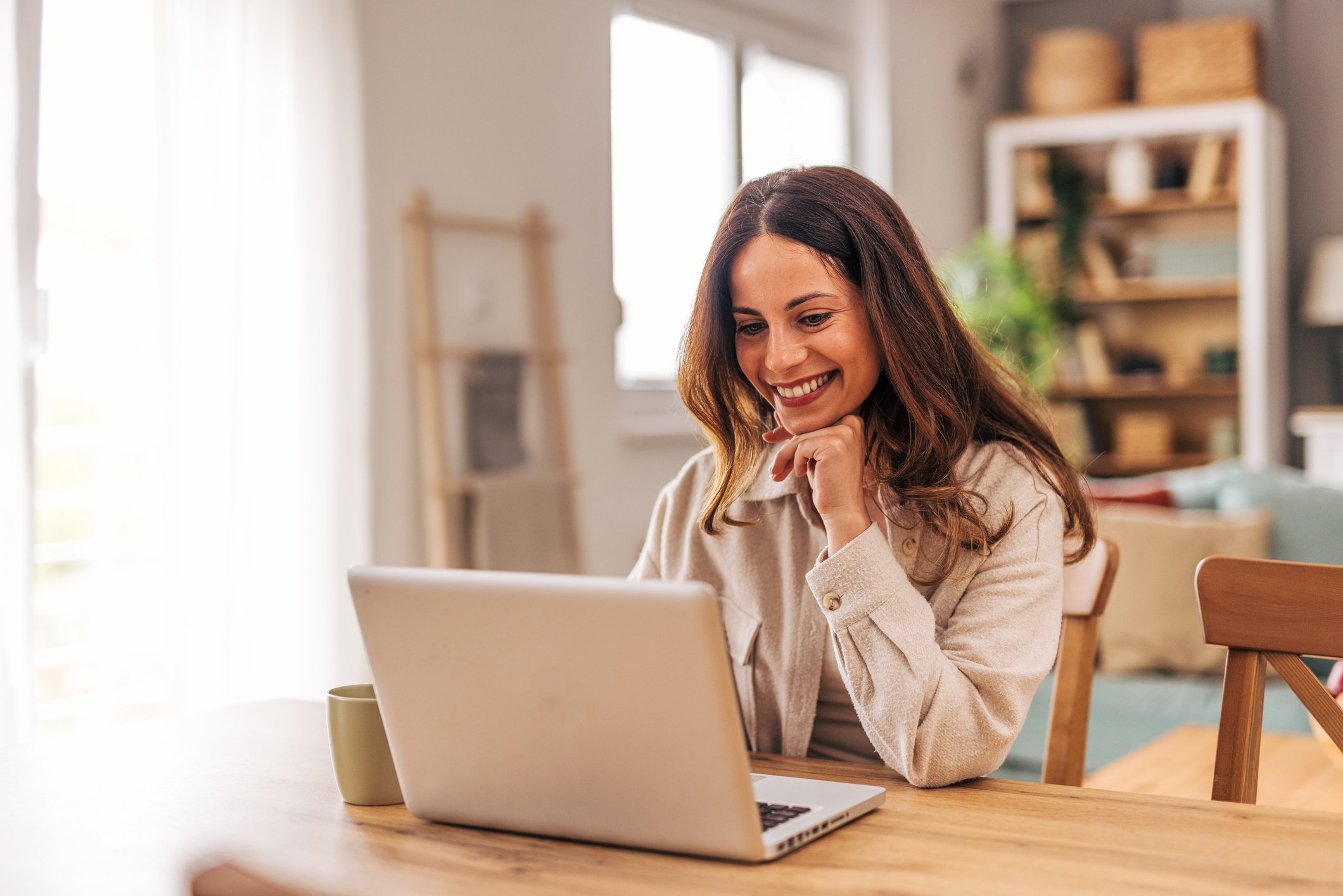 A woman smiling at a laptop.