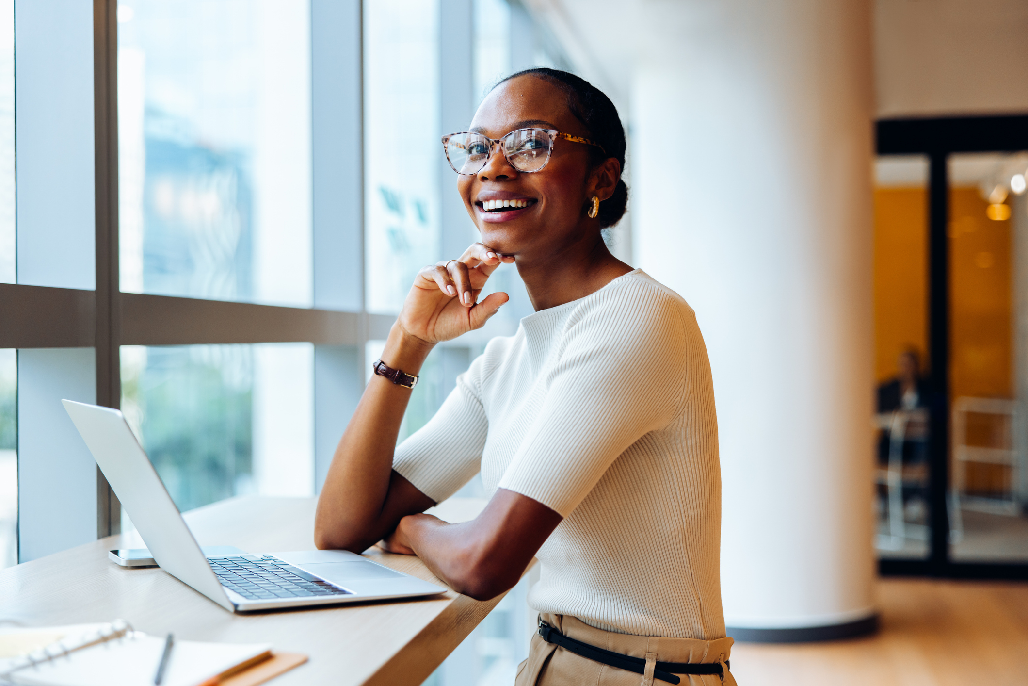 A woman smiling at a laptop.
