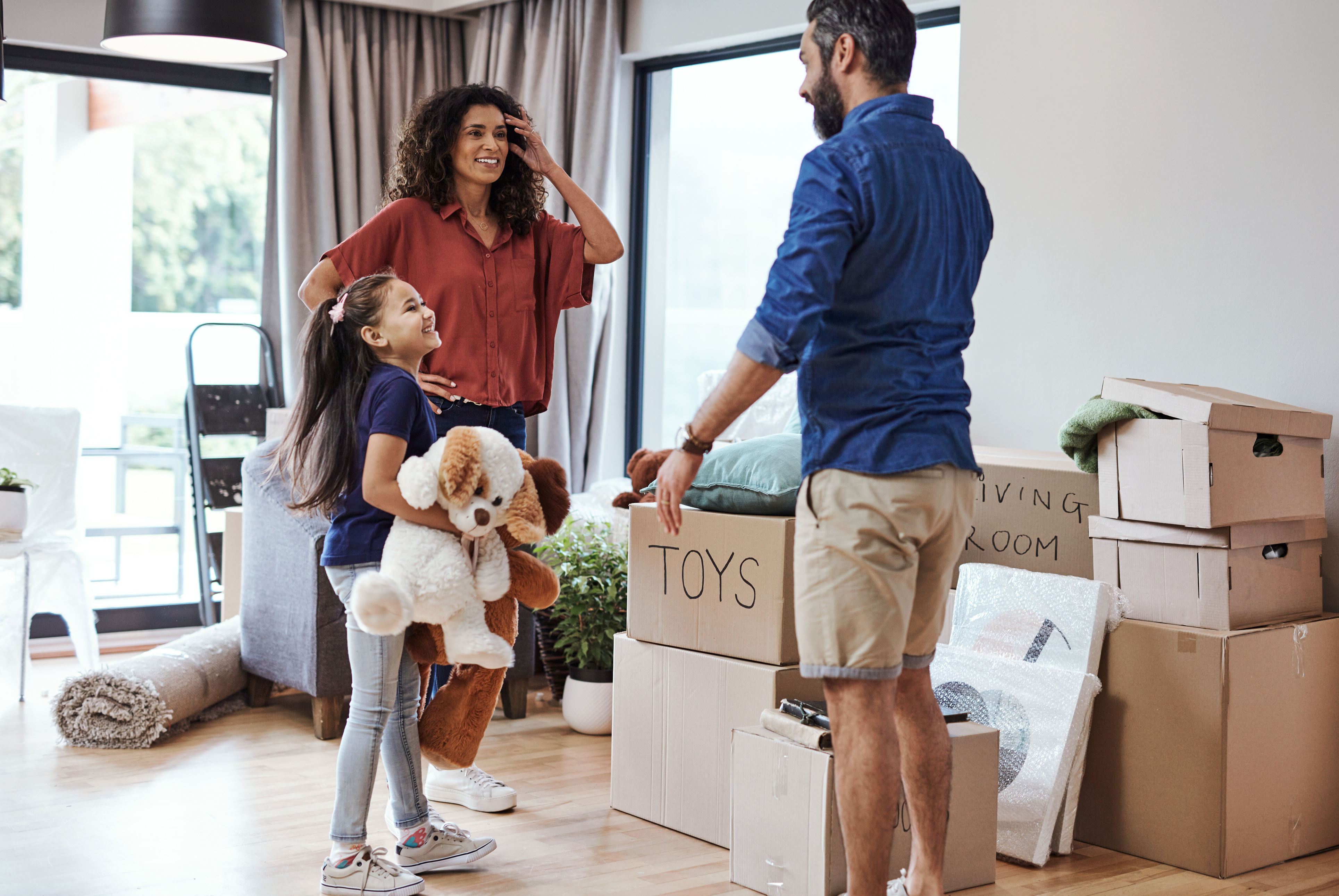 A family of three smiles while moving into a new house.