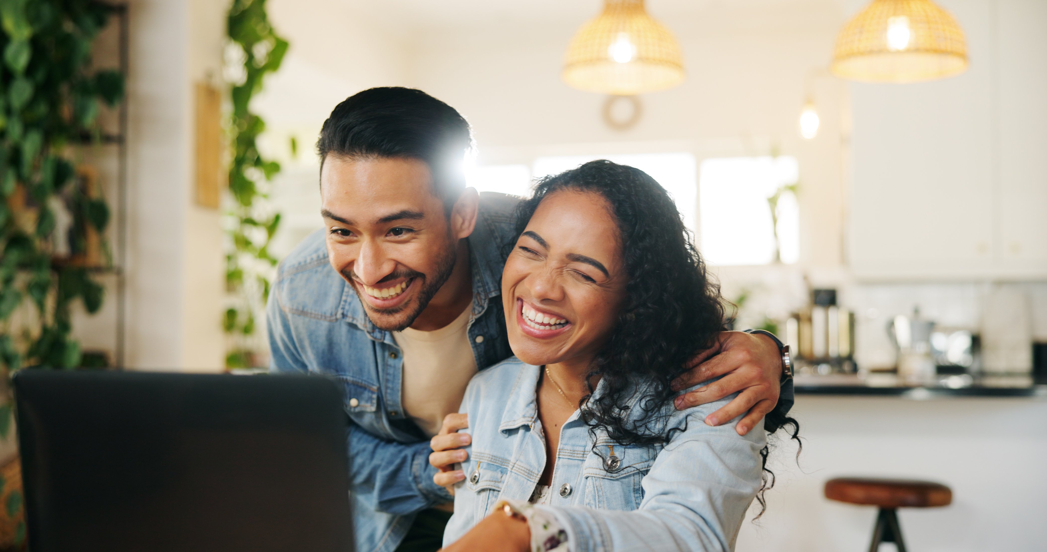 A man and a woman smiling at a laptop