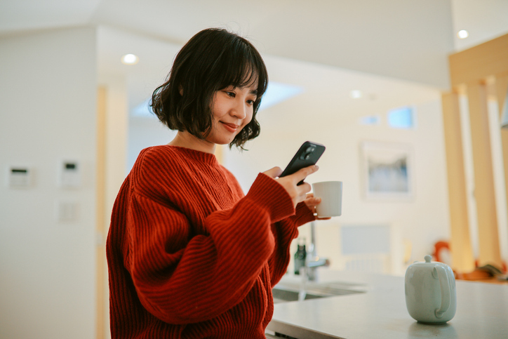 A woman smiles at her phone while looking over her FHA loan closing disclosure.