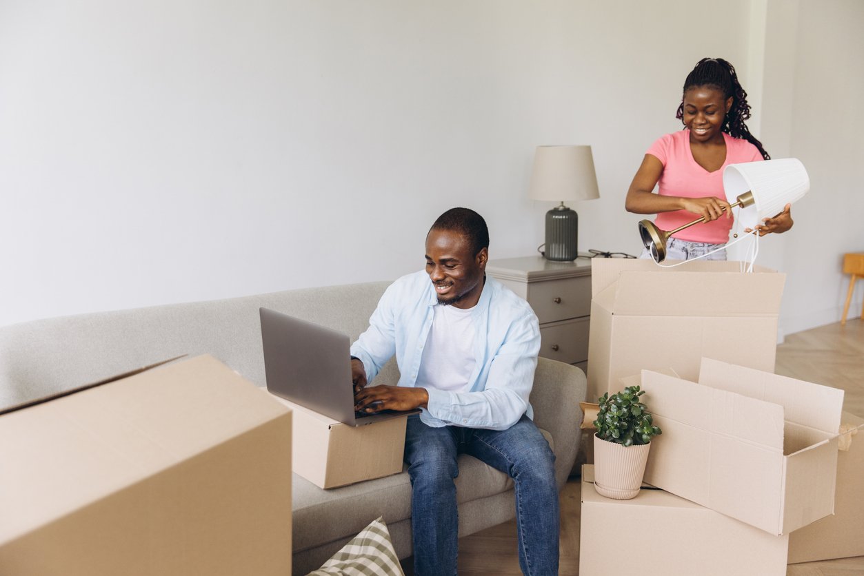 A man and a woman smile while moving into a house