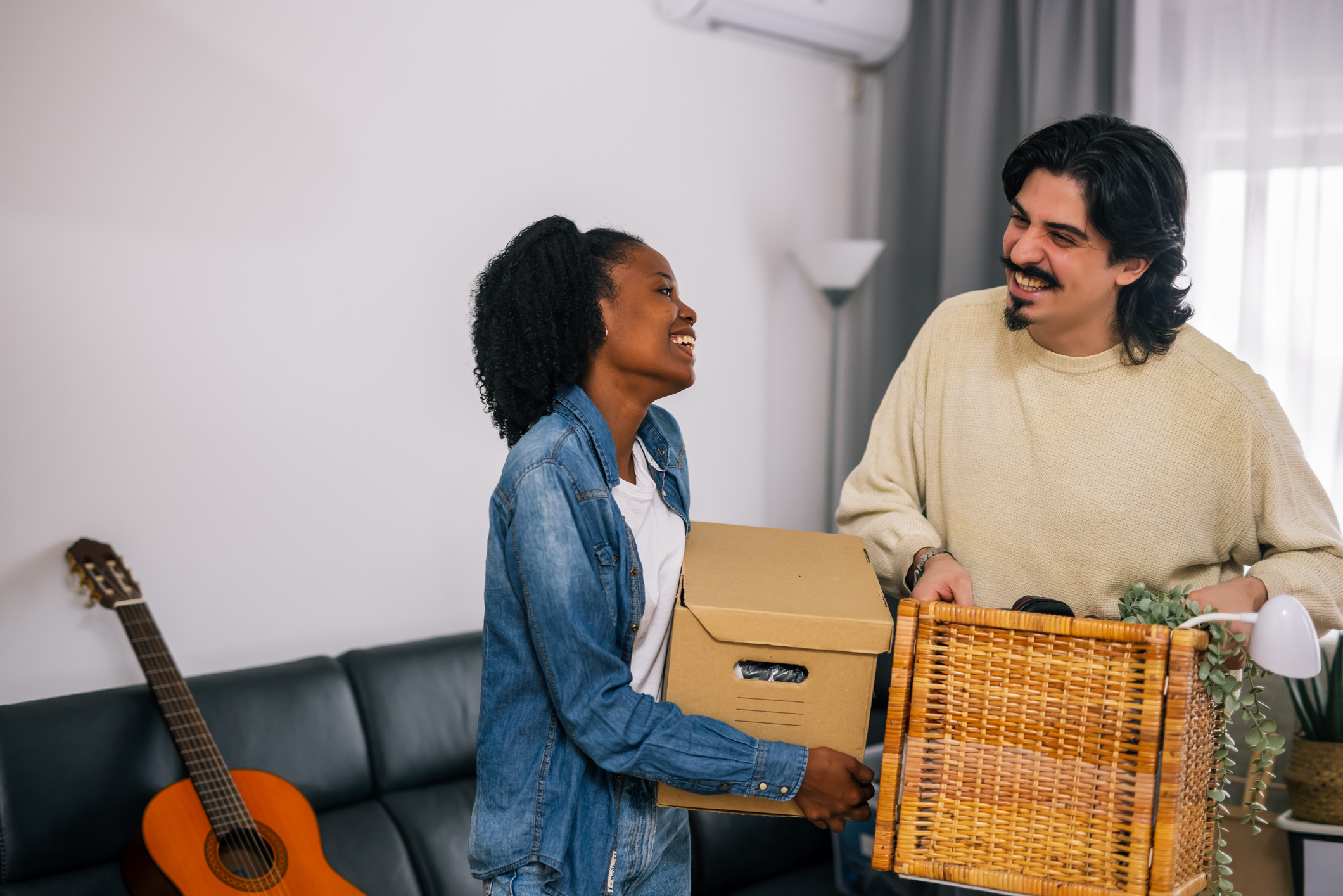 A man and a woman smile while moving boxes.