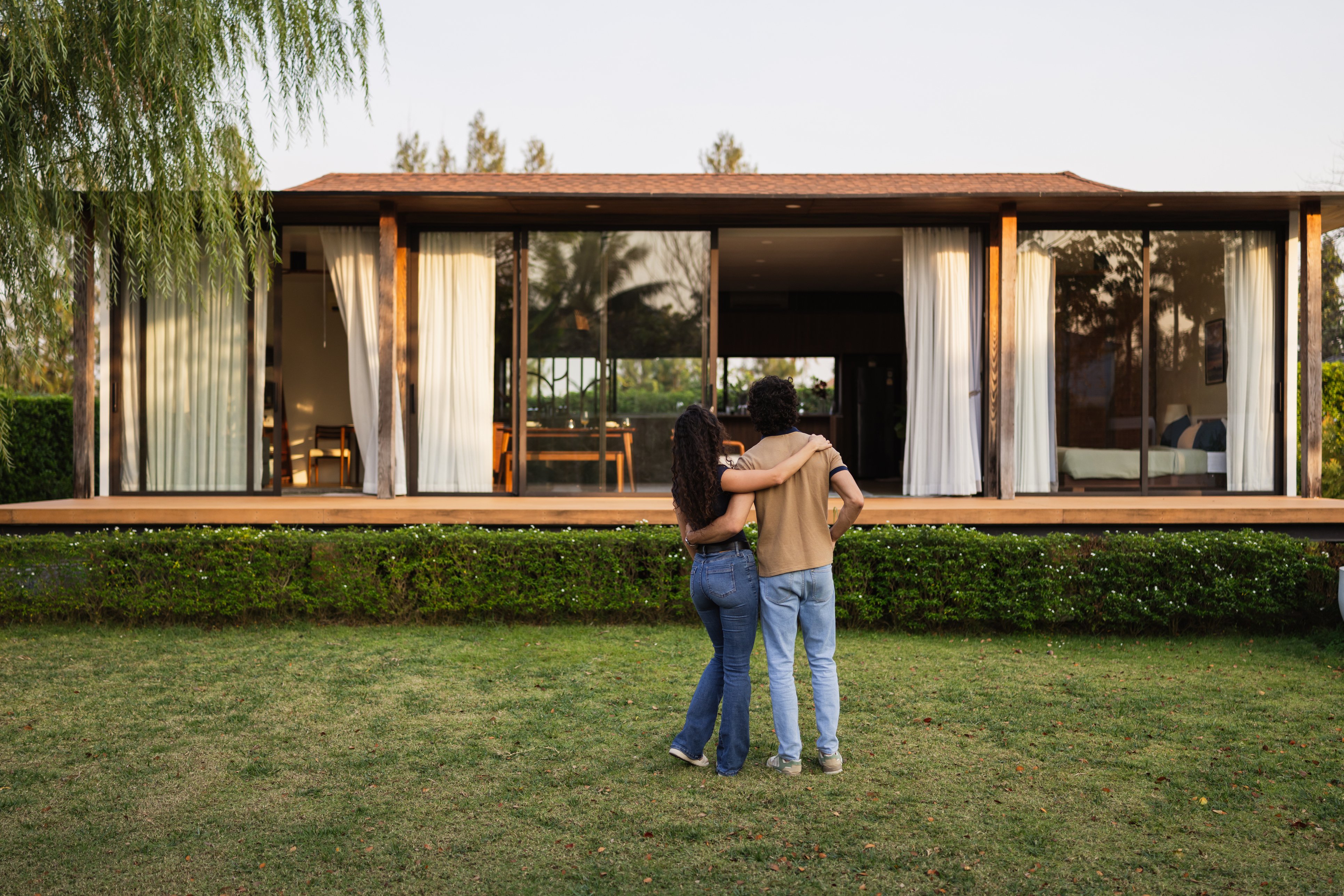 People hug while looking at a house.
