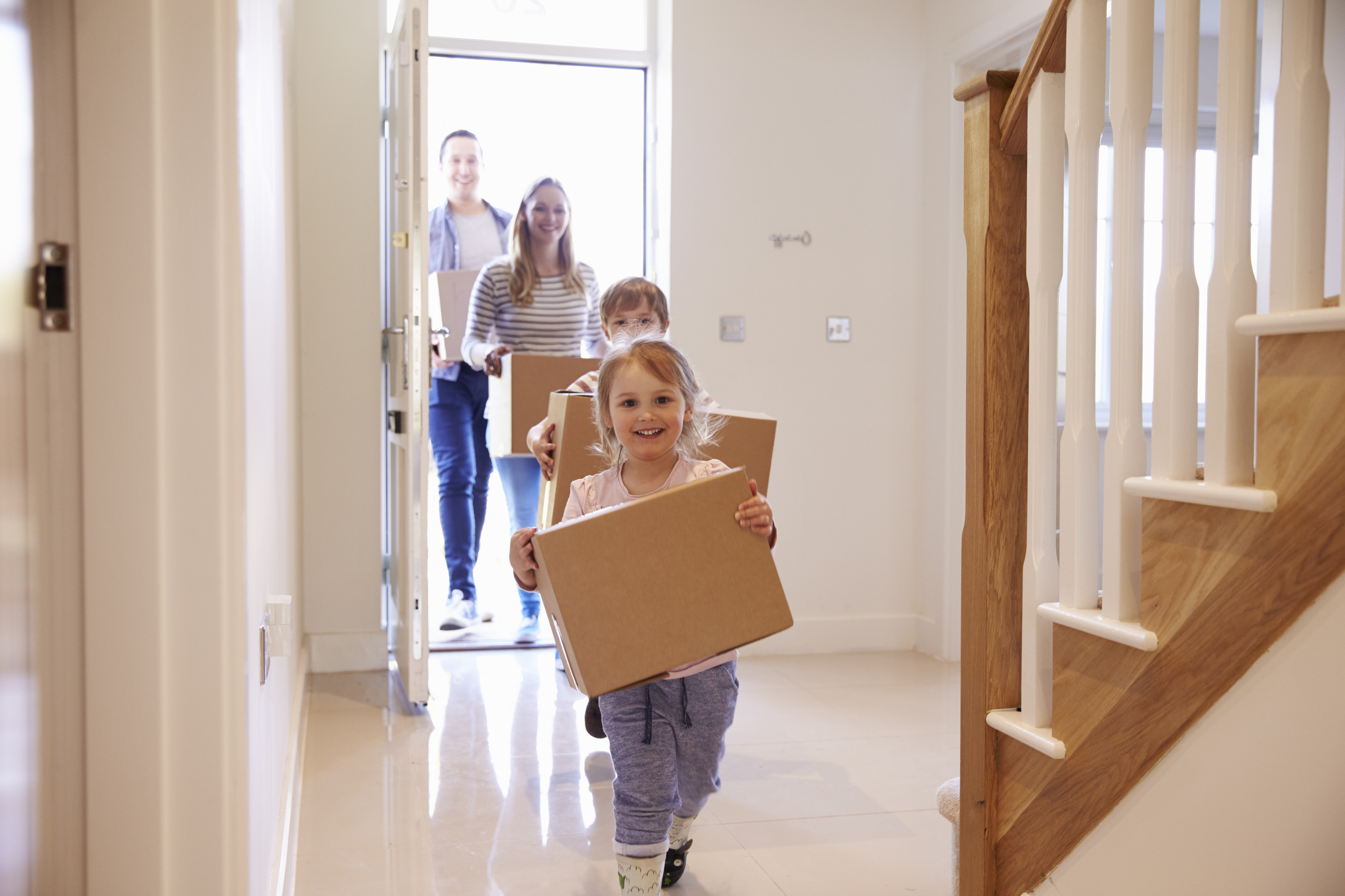 A family carrying boxes into a new home.