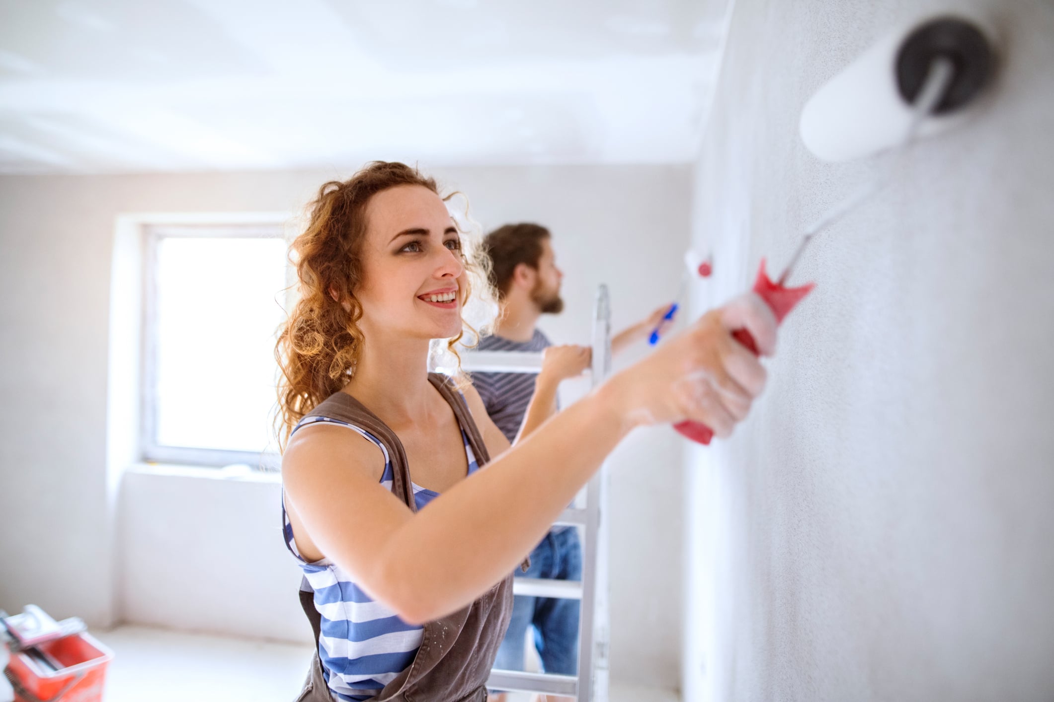 A man and a woman paint the walls in their home.