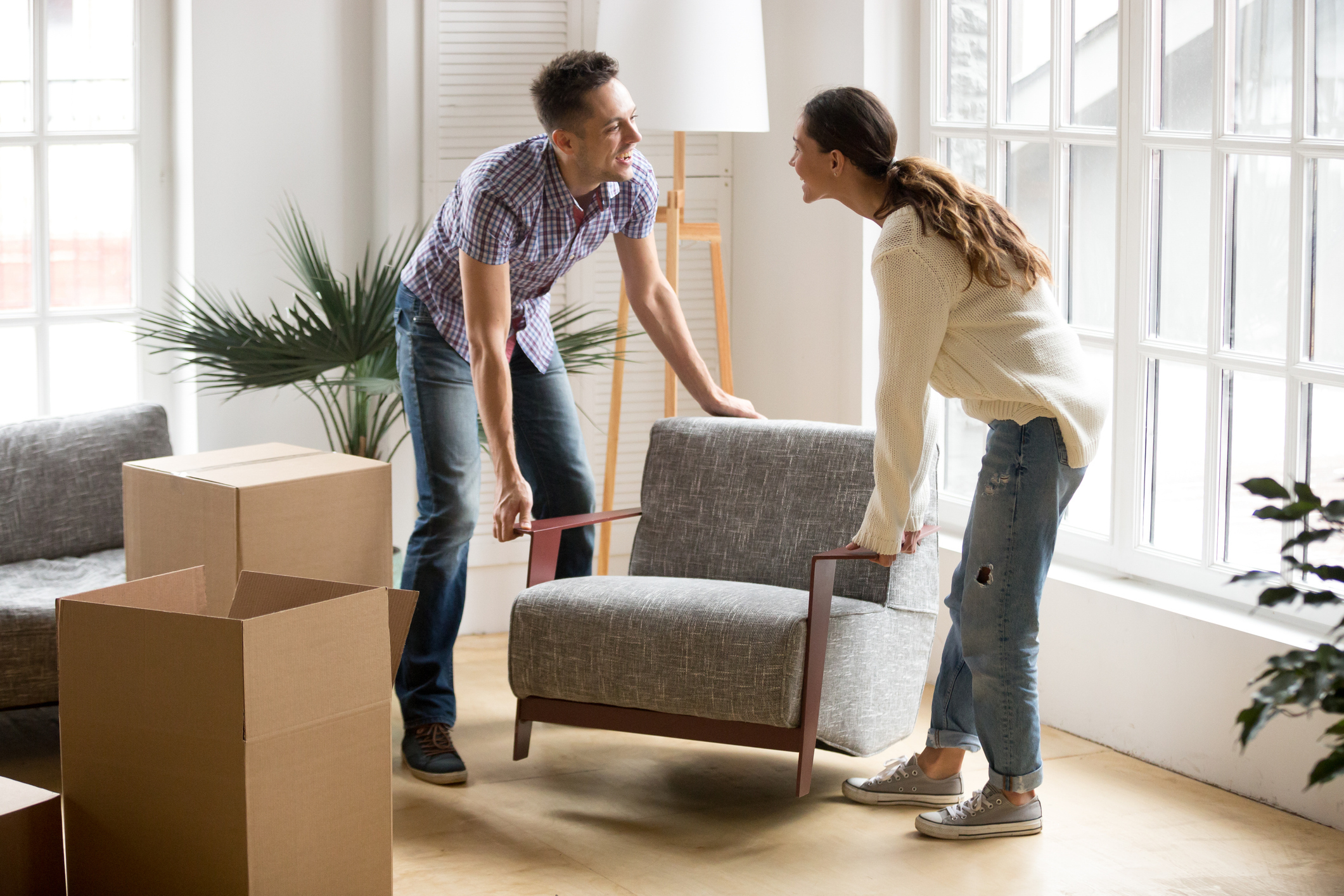 A man and woman smile at each other while moving a chair.