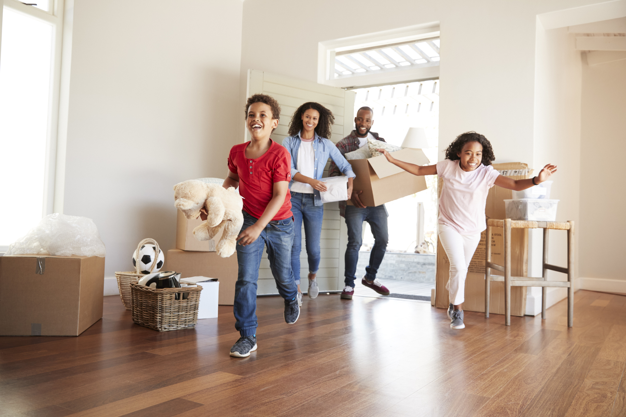 A family smiles while running into a new house.