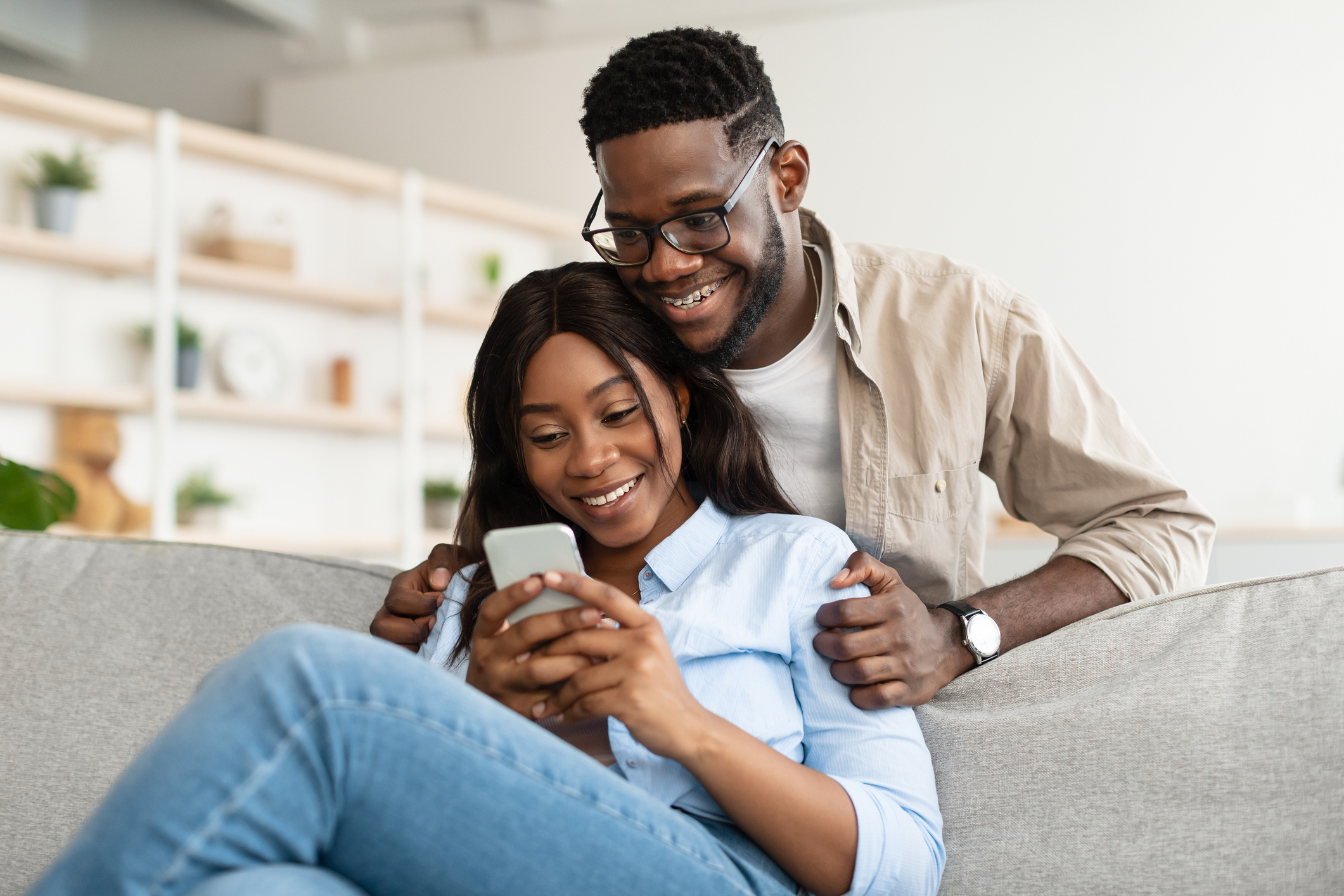 A couple smiles at a phone while comparing mortgage options.
