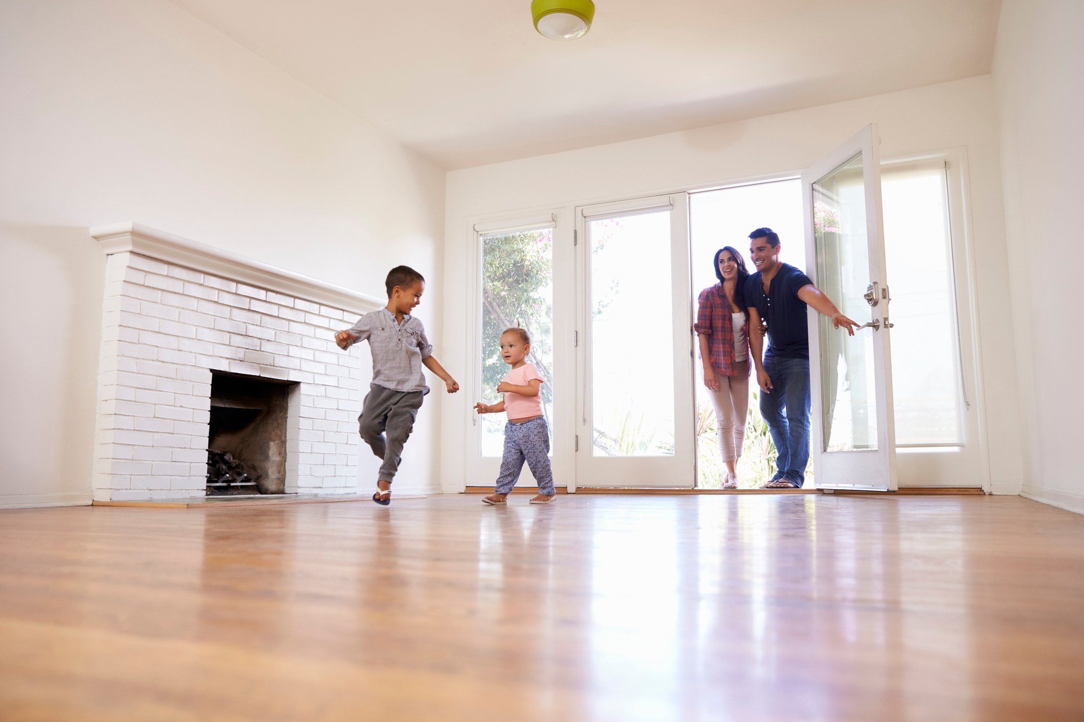 A family smiles while running into a new home.
